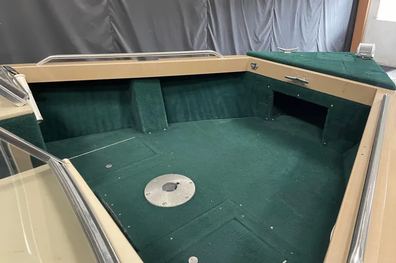 Slide: The Image of 1997 Lund 1700 Pro Sport boat interior with green carpet and storage compartments. - 9