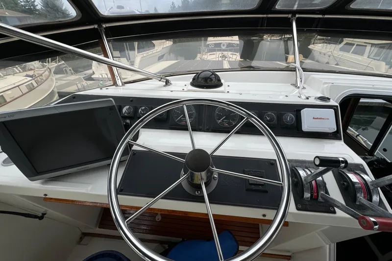 Slide: The Image of 1989 Bayliner 4588 Pilothouse Motor Yacht helm with steering wheel and navigation controls. - 10