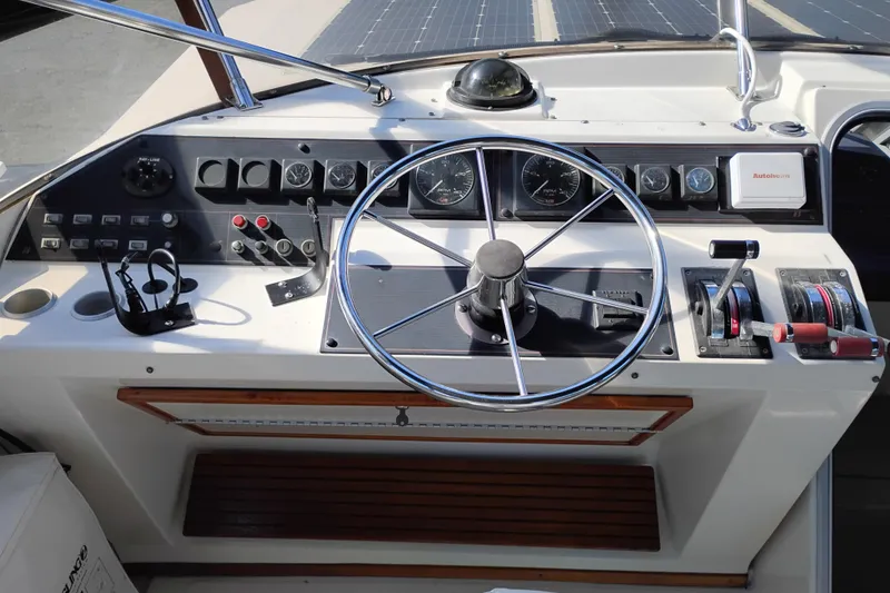 Slide: The Image of 1989 Bayliner 4588 Pilothouse helm with steering wheel, controls, and gauges. - 13