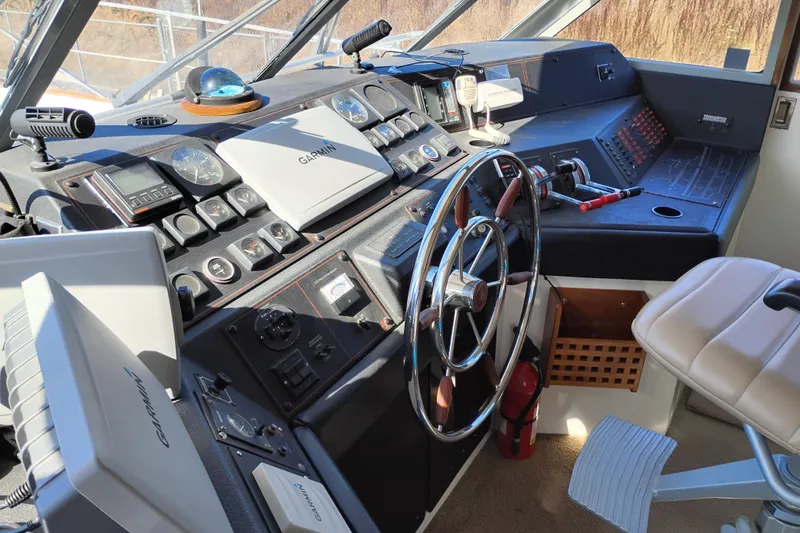 Slide: The Image of 1989 Bayliner 4588 Pilothouse helm with Garmin navigation, steering wheel, and control panel. - 23