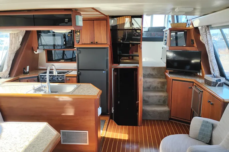 Slide: The Image of 1989 Bayliner 4588 Pilothouse interior with kitchen, stairs, and seating area. - 24