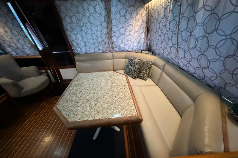 Slide: The Image of 1989 Bayliner 4588 Pilothouse Motor Yacht interior with cushioned seating and patterned curtains. - 29