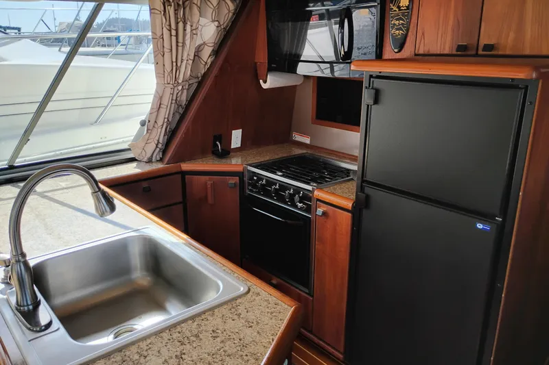 Slide: The Image of 1989 Bayliner 4588 Pilothouse kitchen with sink, stove, and refrigerator. - 31
