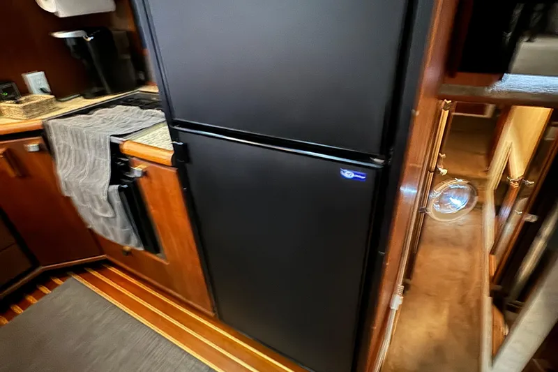 Slide: The Image of 1989 Bayliner 4588 Pilothouse Motor Yacht kitchen with black fridge and wooden cabinetry. - 32