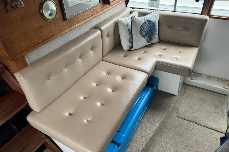 Slide: The Image of 1989 Bayliner 4588 Pilothouse Motor Yacht interior with beige tufted seating and decorative pillows. - 35