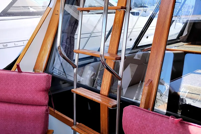Slide: The Image of Interior of 1989 Bayliner 4588 Pilothouse with wooden ladder and pink cushions. - 4