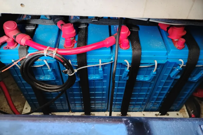Slide: The Image of Battery compartment of 1989 Bayliner 4588 Pilothouse with secured blue batteries and red cables. - 52