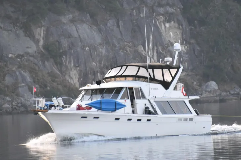 Slide: The Image of 1989 Bayliner 4588 Pilothouse yacht cruising near rocky shoreline. - 57