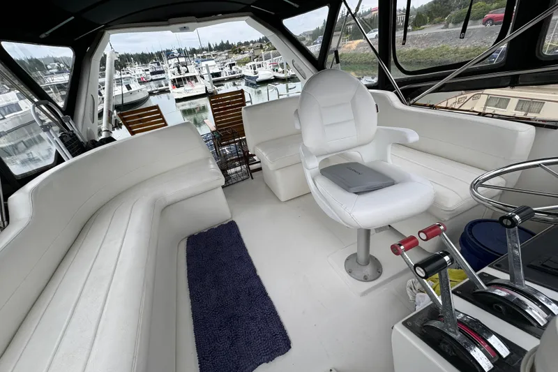 Slide: The Image of 1989 Bayliner 4588 Pilothouse Motor Yacht interior with white seating and marina view. - 6
