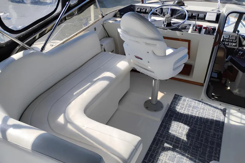 Slide: The Image of 1989 Bayliner 4588 Pilothouse interior with helm, white seating, and nautical decor. - 7