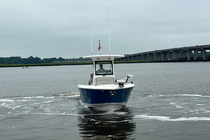 Slide: The Image of 2023 Pursuit S 268 Sport boat cruising on a calm river near a bridge. - 10