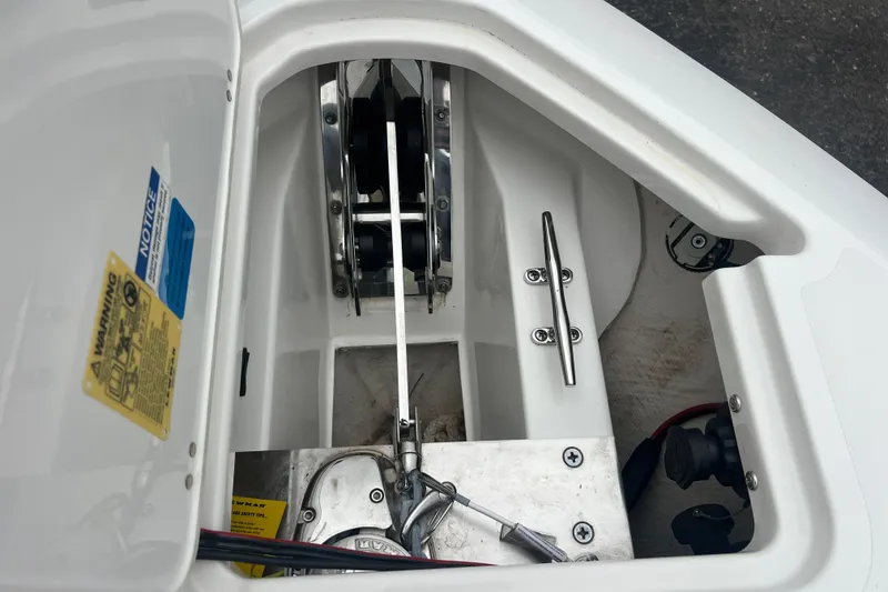 Slide: The Image of 2023 Pursuit S 268 Sport boat anchor compartment with cleat and warning labels. - 23