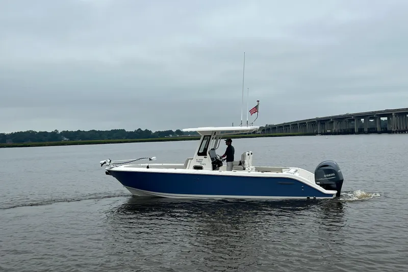 Slide: The Image of 2023 Pursuit S 268 Sport boat cruising on a calm river near a bridge. - 3