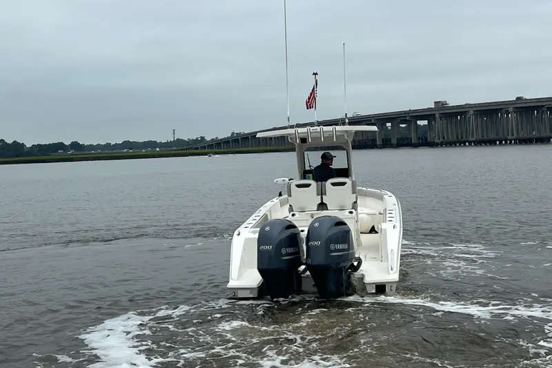 Slide: The Image of 2023 Pursuit S 268 Sport boat cruising on a river near a bridge. - 4