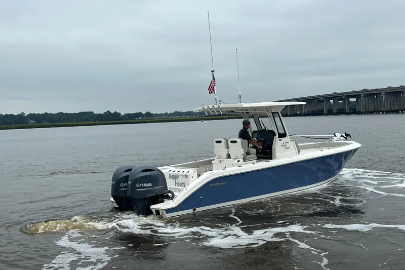 Slide: The Image of 2023 Pursuit S 268 Sport boat cruising on a river near a bridge. - 5
