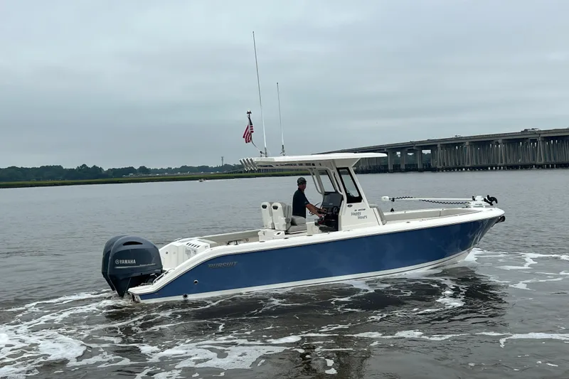 Slide: The Image of 2023 Pursuit S 268 Sport boat cruising on a calm river near a bridge. - 6