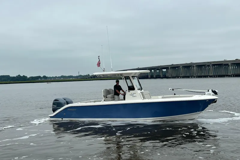 Slide: The Image of 2023 Pursuit S 268 Sport boat on calm water near a bridge. - 7