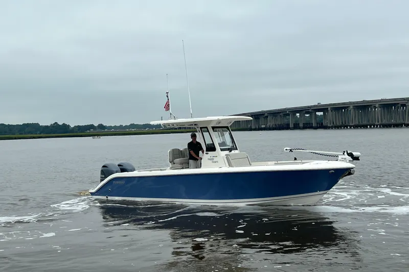 Slide: The Image of 2023 Pursuit S 268 Sport boat cruising on a calm river near a bridge. - 8