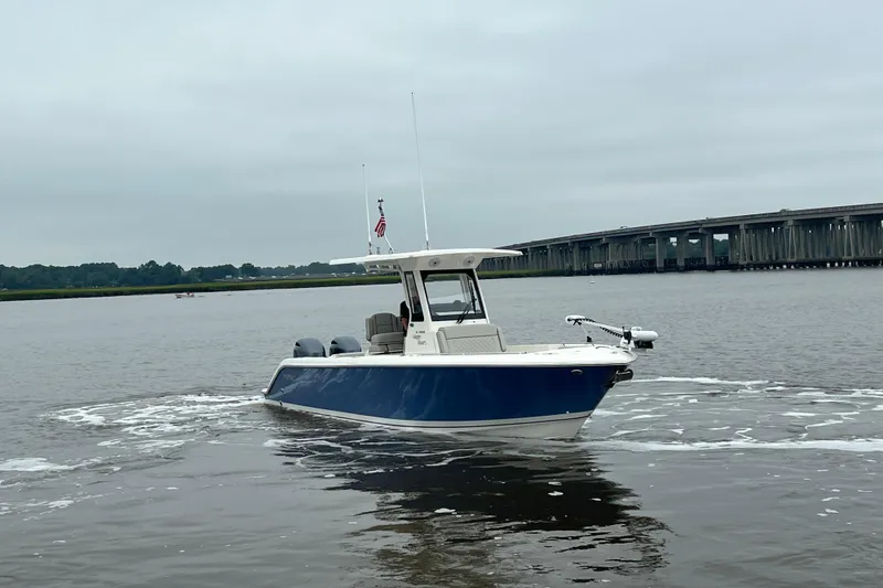 Slide: The Image of 2023 Pursuit S 268 Sport boat cruising on a calm river near a bridge. - 9