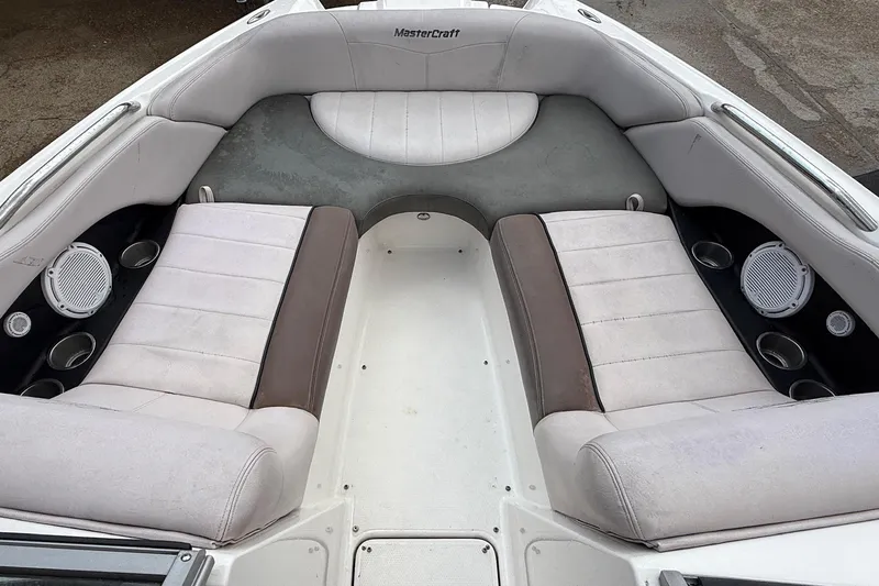 Slide: The Image of 2006 MasterCraft X45 boat interior with white and brown seating, cup holders, and speakers. - 16