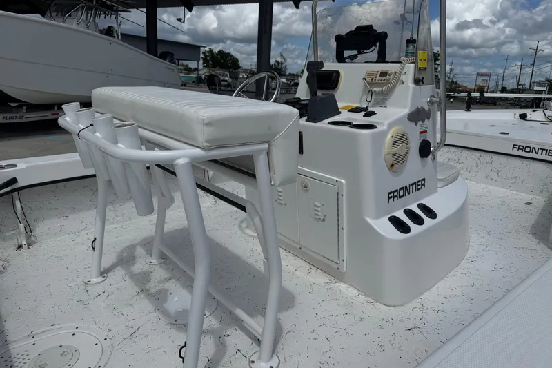 Slide: The Image of 2011 Frontier 2104 boat interior with console and seating, under a cloudy sky. - 12