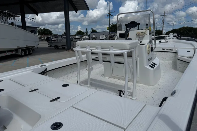 Slide: The Image of White 2011 Frontier 2104 boat interior with seating and console, parked under a canopy. - 14