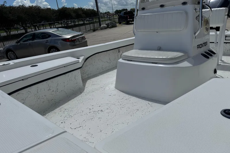 Slide: The Image of 2011 Frontier 2104 boat interior with seating and console, parked near a car. - 15