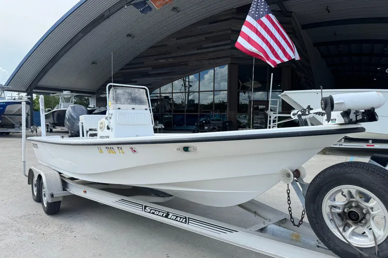 Slide: The Image of 2011 Frontier 2104 boat on trailer, parked outside a showroom with American flag. - 3
