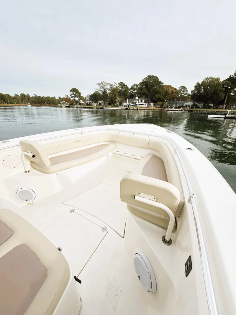 Slide: The Image of 2016 Cobia 296 Center Console boat on calm water, featuring spacious seating and scenic shoreline. - 10