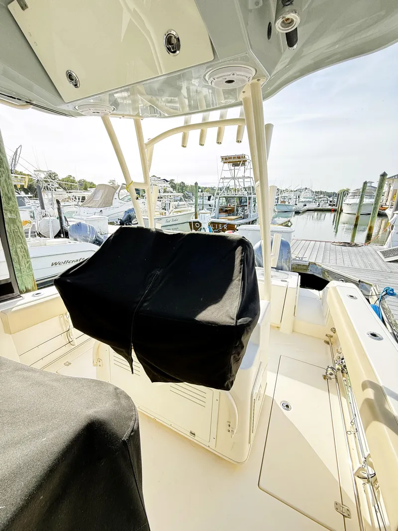 Slide: The Image of 2016 Cobia 296 Center Console boat docked at a marina, featuring covered seating. - 20