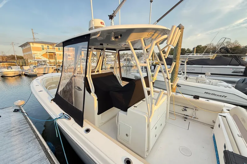 Slide: The Image of 2016 Cobia 296 Center Console boat docked at marina, featuring enclosed helm area. - 25