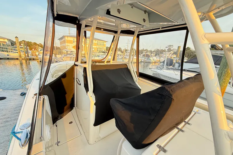Slide: The Image of 2016 Cobia 296 Center Console boat interior at marina, featuring covered seating and helm. - 26