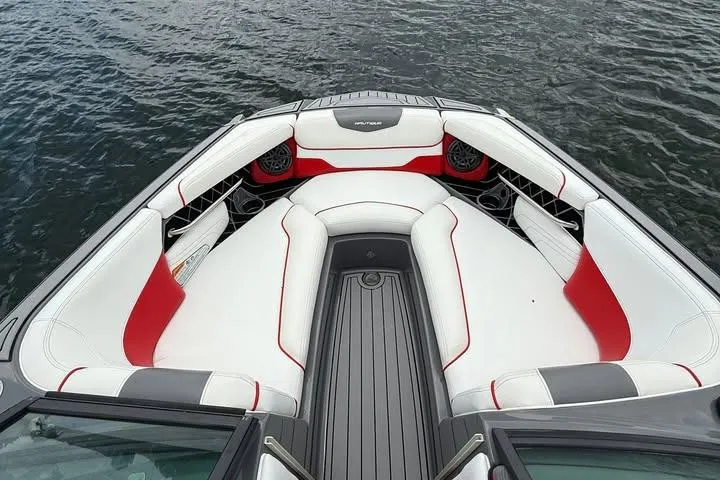 Slide: The Image of 2018 Nautique Super Air Nautique GS22 boat interior with red and white seating on water. - 6
