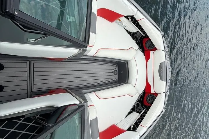 Slide: The Image of 2018 Nautique Super Air Nautique GS22 boat interior with red and white seating on water. - 7