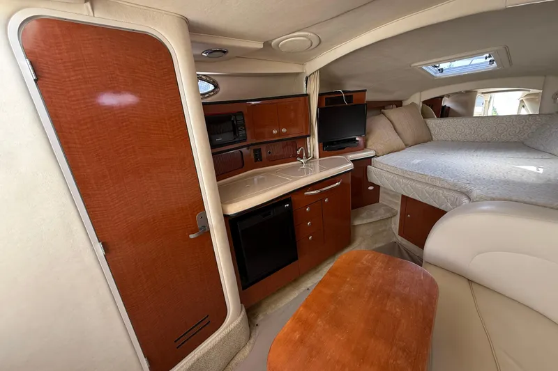 Slide: The Image of Interior of 2005 Sea Ray 300 Sundancer with kitchenette, bed, and seating area. - 14