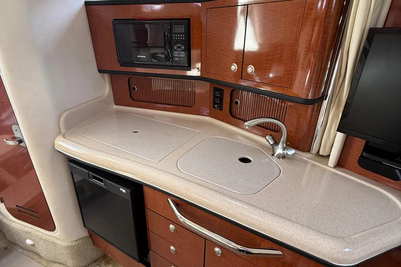 Slide: The Image of 2005 Sea Ray 300 Sundancer galley with sink, microwave, and cabinetry. - 20