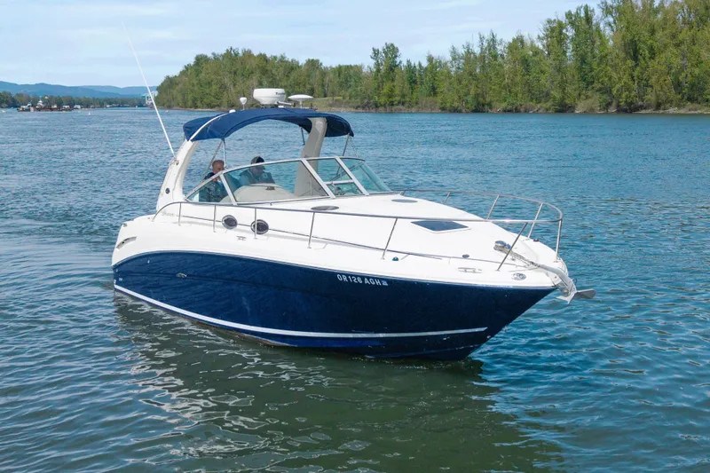 Slide: The Image of 2005 Sea Ray 300 Sundancer cruising on a serene lake with lush green shoreline. - 43