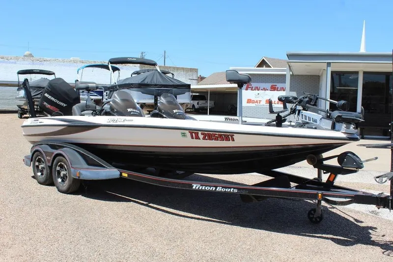 The Image of 2008 Triton Tr21 X boat on trailer, parked outside dealership under clear blue sky. - 1