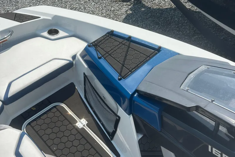 Slide: The Image of 2021 Scarab 165 ID boat on trailer, white and blue design, parked on gravel. - 3