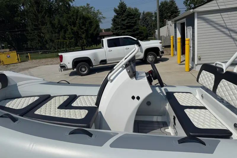 Slide: The Image of 2025 Highfield Sport 390 boat with white quilted seats, parked near a white truck. - 9