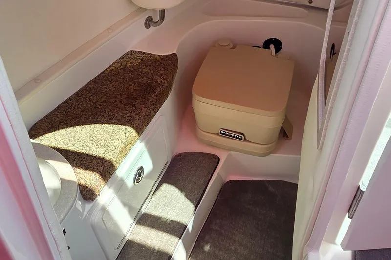 Slide: The Image of 2003 Cobalt 282 boat interior with portable toilet and cushioned seating. - 15