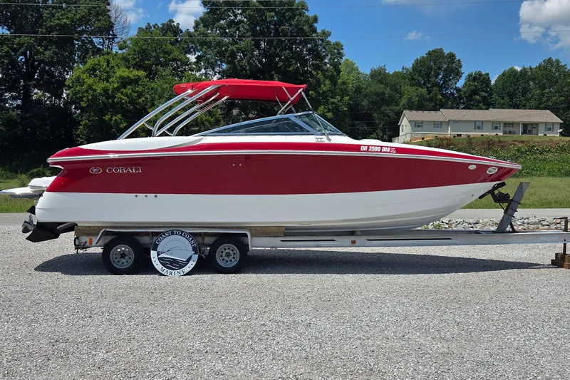 Slide: The Image of 2003 Cobalt 282 boat with red and white design on a trailer, outdoors. - 2