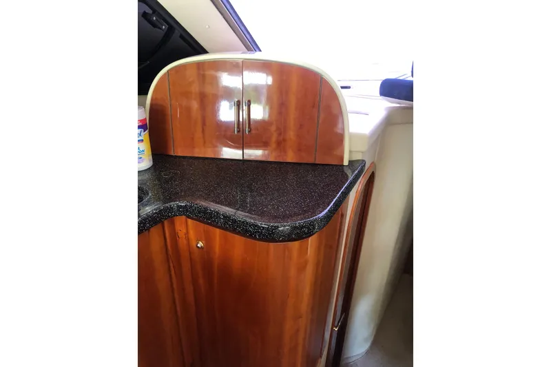 Slide: The Image of Birchwood Challenger 460 Flybridge 2002 interior with polished wood cabinetry and black countertop. - 77