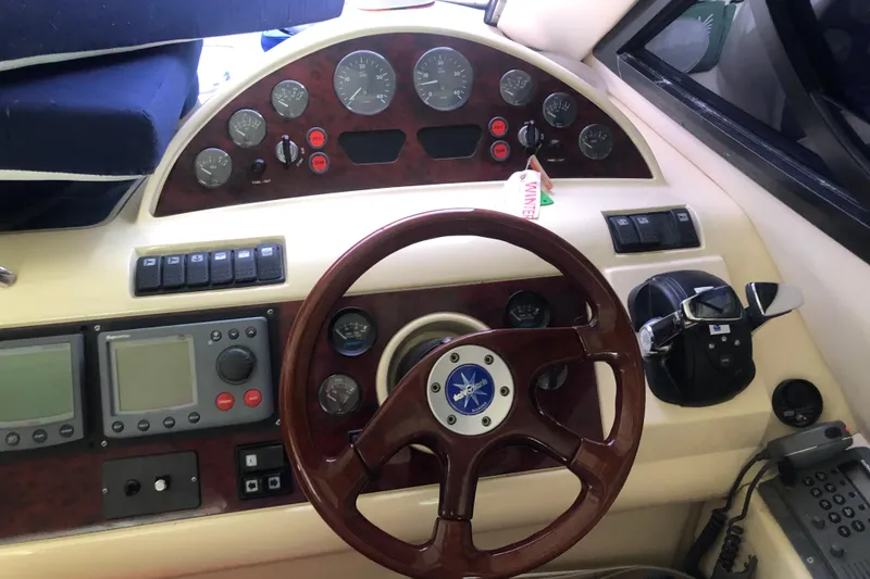Slide: The Image of Birchwood Challenger 460 Flybridge 2002 helm with gauges, controls, and wooden steering wheel. - 90
