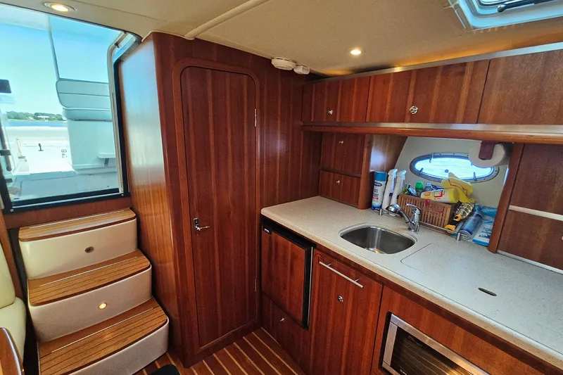 Slide: The Image of 2006 Tiara 3200 Open yacht interior with wooden cabinetry, kitchenette, and stairs. - 34