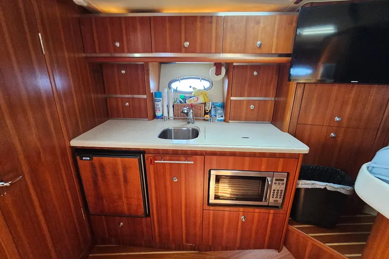 Slide: The Image of 2006 Tiara 3200 Open yacht interior kitchen with wood cabinetry, sink, and microwave. - 35