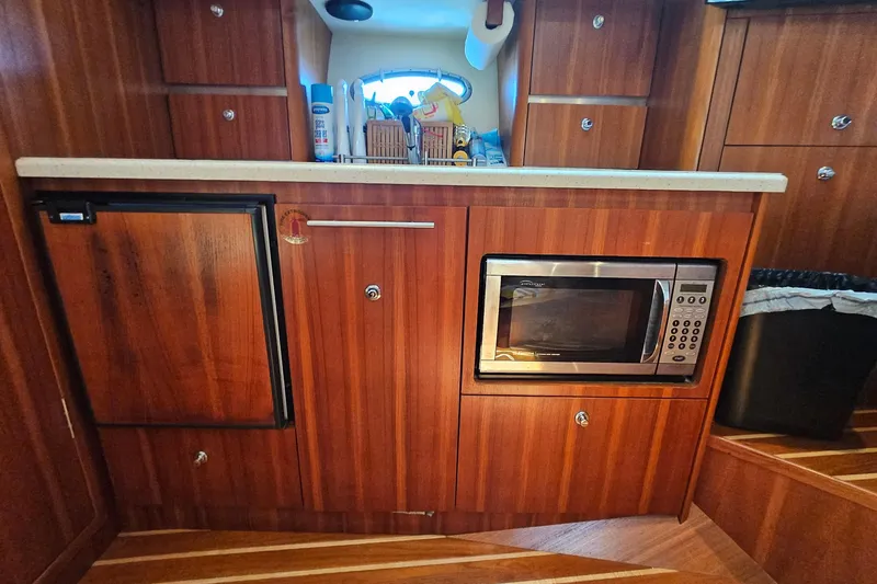 Slide: The Image of 2006 Tiara 3200 Open yacht kitchen with wood cabinetry, microwave, and compact fridge. - 36