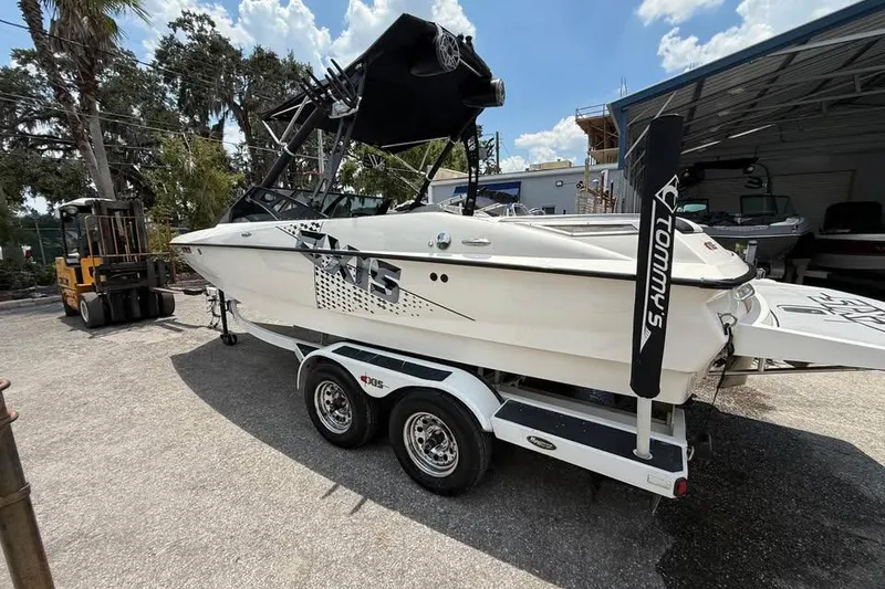 Slide: The Image of 2011 Axis A20 boat on trailer, parked outdoors under a sunny sky. - 2