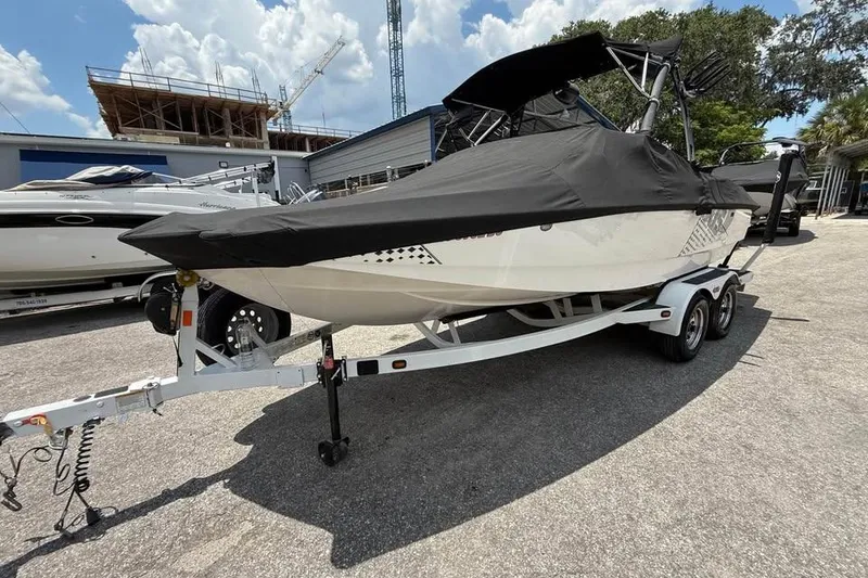 Slide: The Image of 2011 Axis A20 boat on trailer, covered, parked outdoors under a partly cloudy sky. - 4