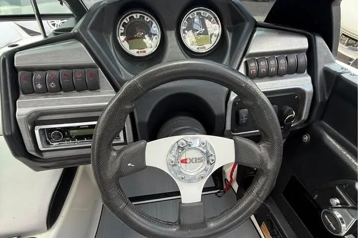 Slide: The Image of Steering wheel and dashboard of a 2011 Axis A20 boat, featuring gauges and controls. - 5